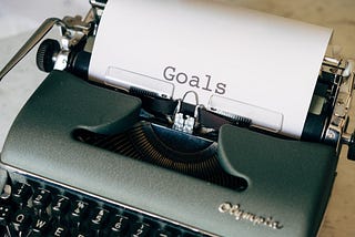 “Goals” written in big letters on a white page in a military green typewriter