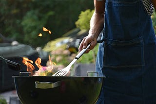 Man in an apron cooks on a barbeque