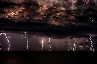A dark thunderstorm shoots multiple lightning bolds to the ground.