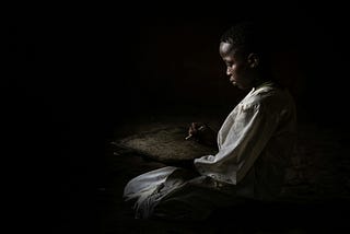 Young boy sitting in the dark.