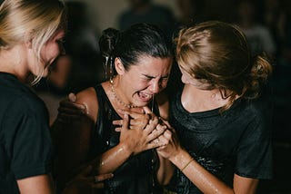 Woman crying, supported by her friends