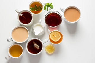 various cups of tea from black with milk to herbal with lemon on white background