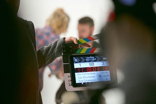 A film set clapboard in front of unfocused actors