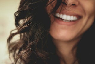 Close-up of a smiling woman’s mouth, framed by curly dark hair