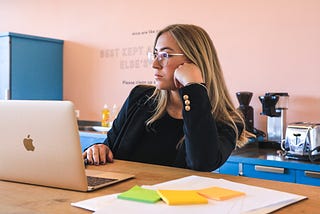 Woman leans on her arm while in front of a laptop