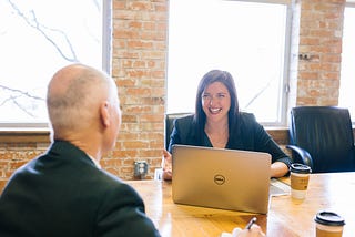 Girl at a desk talking to a man across the table