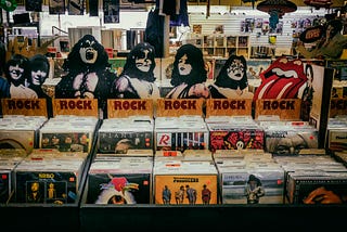 Picture of a record store with 12 inch records in front and KISS merch in the back.