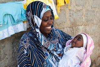 Miza Juma Juma, a new mom in Tanzania, smiles lovingly at her newborn baby, Umulayman, who she is cradling in her arms.