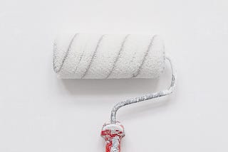 A paint roller with white paint on it, lying on a white background