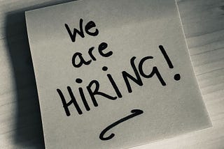 Black and white photo of a post-it with ‘We are hiring!’ written on it