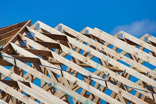 The exposed roof trusses of a home under construction shows the wood used to build them.