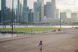 A woman walking away from the camera with Singapore’s CBD in the background.