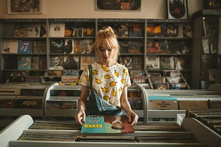 A young woman in a colourful T-shirt browses records in a vinyl record store