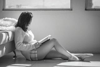 Girl sitting on floor reading a book.