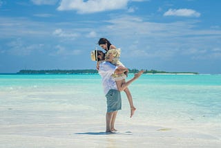 A wide shot of a couple on a beach in the Maldives, one of the best honeymoon destinations in Asia
