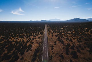 Aerial photo of a long stretch of highway traveling off into the mountains.