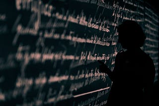 Shadow of person writing many lines of cursive on chalkboard