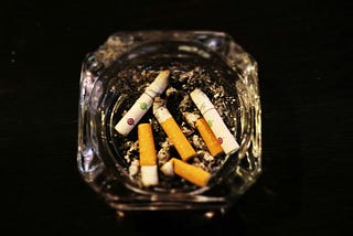 an ash tray with cigarette butts According to the Moon by Jim Latham