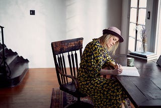 Woman writing in chair by window