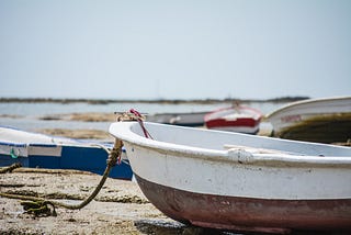 Boats sitting on a beach at low tide.