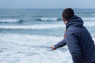 Man throwing rock into ocean