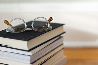 a stack of books with a pair of glasses on top