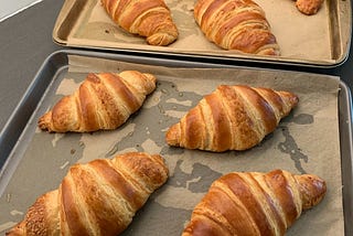 eight golden brown croissants on two baking sheets