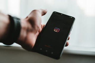 holding a phone with instagram logo