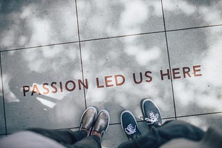 Two people standing on a stone path. The words “Passion led us here” are printed on the path.