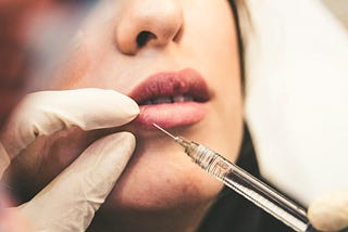 A woman getting filler injected into her lips.