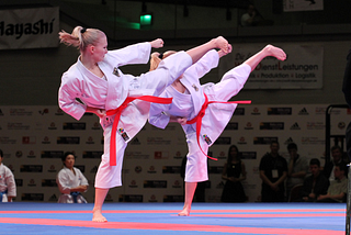 Two women kicking during a karate tournament