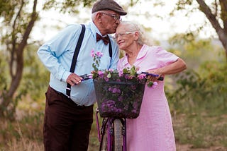 A man kissing his elderly wife on the head as they interrupted their ride