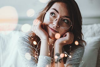 brunette woman wearing a white shirt and gold rimmed glasses