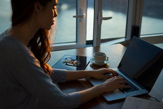 Woman sitting at a laptop typing.