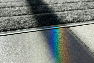 an abstract photo of two concrete slabs joining on the road with a rectangular prism shining onto one and and an extended rectangular shadow on the other.