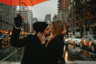 man and woman kissing under an umbrella