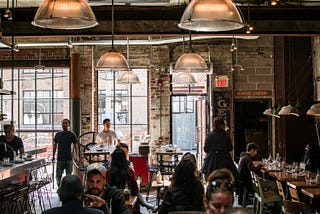 Busy restaurant interior with diners eating and staff moving between tables.
