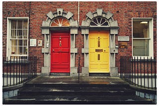 Row housing with two doors to choose, one yellow on the right and a red one on the left.