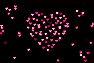 Small purple and pink hearts creates a giant heart in black background.