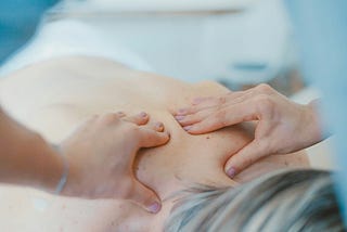 A therapist hands massaging a client’s back.