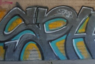 Grey graffiti letters on a brick wall.
