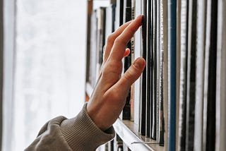 A hand reaching out for a book in the library.