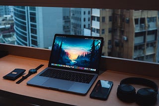A picture of a laptop, phone, smartwatch and a window side