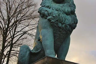 a statue of blueish lion looking upward to the sky