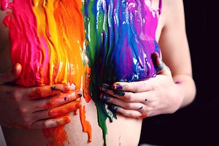 Rainbow paint colors streaming down a person bare chest