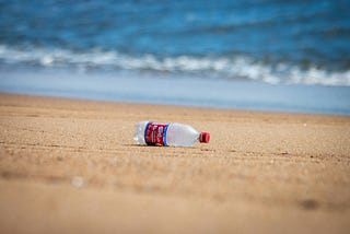 A plastic bottle washes up on the beach of the ocean. Earthday, reduce, reuse, conservation, environment