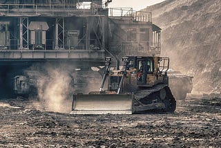 Gray photo of a bulldozer in a large coal pit.