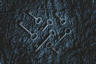 A black background with 7 metal keys lying on it.