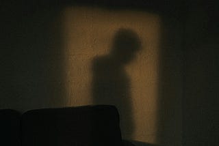 sad dark room, a man’s shadow, head down
