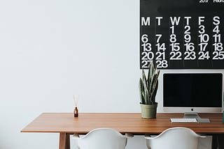 office desk with Mac, plant, and calendar